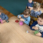 Troje dzieci wykonuje wodny eksperyment przy stoliku.
