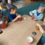 Czworo dzieci wykonuje wodny eksperyment przy stoliku.