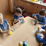 Czworo dzieci wykonuje wodny eksperyment przy stoliku.