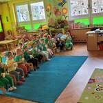Dzieci siedzą na krzesełkach i oglądają film edukacyjny.