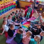 Dzieci siedzą w kole z kolorowymi skarpetami na stopach.