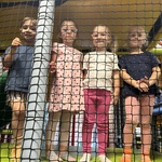 Czworo dzieci stoi na torze przeszkód w sali zabaw.