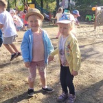 Dwie dziewczynki tańczą na placu zabaw, trzymając się za ręce.