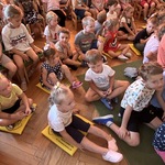 Dzieci siedzą na dywanie i oglądają teatrzyk.