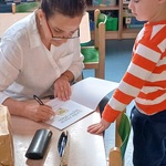 Autorka wpisuje dedykację do książki dla chłopca.