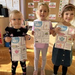 Trzy dziewczynki trzymają przed sobą karty pracy z j. angielskiego.