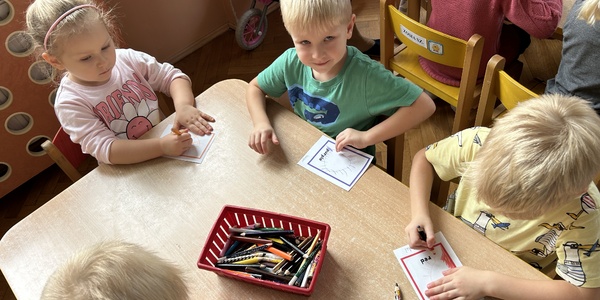 Dzieci wykonują pracę z j. angielskiego przy stoliku.