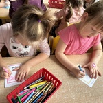 Dwie dziewczynki wykonują prace z j. angielskiego przy stoliku.