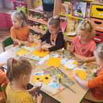 Dzieci wykonują pracę plastyczną przy stoliku.