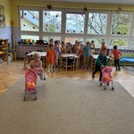Dzieci wiozą pluszowe dynie w wózkach dla lalek podczas wyścigów rzędów.