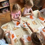 Dzieci z grupy II stemplują pomarańczową farbą rycinę dyni.