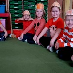 Dzieci z grupy VI siedzą na dywanie w opaskach z rysunkiem dyni.