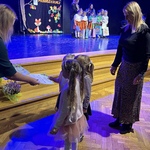 Trzy dziewczynki wraz z nauczycielką odbierają nagrodę w konkursie piosenki.
