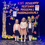 Trzy dziewczynki pozują do zdjęcia podczas konkursu piosenki.