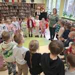 Dzieci stoją w kolę wraz z panią bibliotekarką podczas zajęć edukacyjnych.