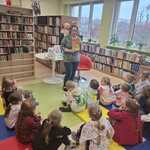 Dzieci z grupy IV słuchają pani bibliotekarki podczas zajęć edukayjnych.