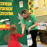 Dziewczynka odbiera nagrodę z rąk nauczycielki.
