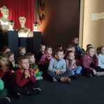 Dzieci oglądają film edukacyjny, w tle popiersia.