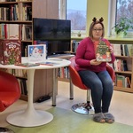 Pani bibliotekarka trzyma książkę o tematyce świąteczej.