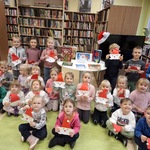 Grupowe zdjęcie dzieci z grupy III Smerfy w bibliotece z wykonanymi pracami plastycznymi.