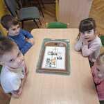 Dzieci układają planszę edukacyjną z odpadami.