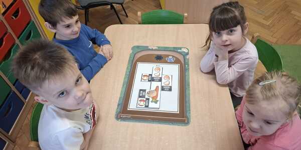 Dzieci układają planszę edukacyjną z odpadami.