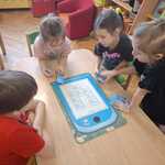 Dzieci układają planszę edukacyjną z odpadami.