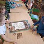 Dzieci układają planszę edukacyjną z odpadami.