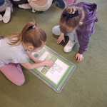 Dzieci układają planszę edukacyjną z odpadami.