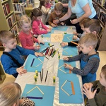 Dzieci wykonują pracę plastyczną przy stoliku.