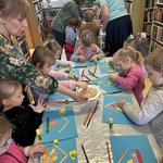 Dzieci wykonują pracę plastyczną przy stoliku.