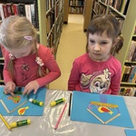 Dzieci wykonują pracę plastyczną przy stoliku.