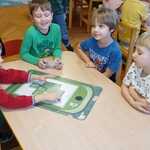 Dzieci układają planszę edukacyjną z odpadami.