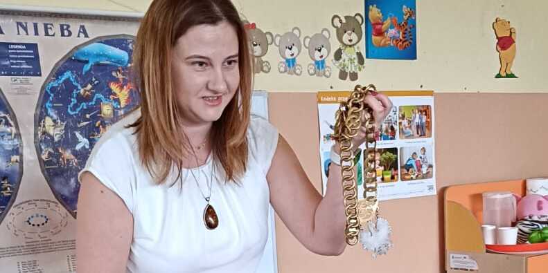 Mama-sędzia prezentuje dzieciom łańcuch sędziowski.