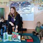 Mama-sędzia w todze sędziowskiej czyta dzieciom bajkę.