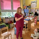 Pielęgniarka ubrana w scrubs medyczny prezentuje dzieciom probówki do pobierania krwi.