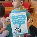 Chłopiec trzyma planszę edukacyjną.