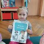 Dziewczynka trzyma planszę edukacyjną.