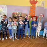 Dzieci ubrane na niebiesko trzymają ulotki informacyjne o owsikach.