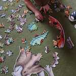Chłopiec układa puzzle z dinozaurami.