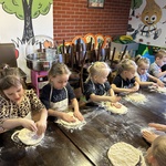 Dzieci rozgniatają ciasto na pizzę.
