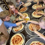 Dzieci nakładają dodatki na pizze.