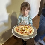 Dziewczynka niesie pizzę.