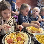 Dzieci nakładają dodatki na pizze.