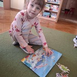 Dziewczynka prezentuje swoją książkę na temat dinozaurów. 