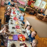 Dzieci siedzą przy stole i uśmiechają się do fotografa.