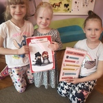 Dziewczynki trzymają w rękach kartki, na których są zapisane zasady zachowania w teatrze oraz pokazani są aktorzy.