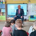 Mężczyzna siedzi na krześle i rozmawia z dziećmi.