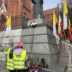 Dzieci składają znicz i kwiaty pod pomnikiem papieża