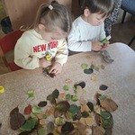 Dzieci wykonują pracę plastyczną z wykorzystaniem liści.
